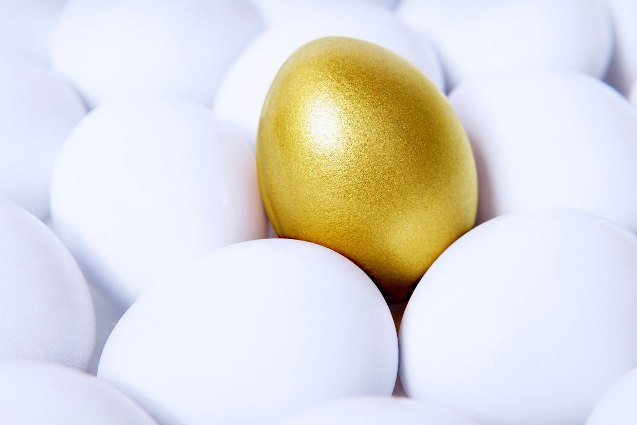 Ein Bild mit einem goldenen Ei inmitten weißer Eier.